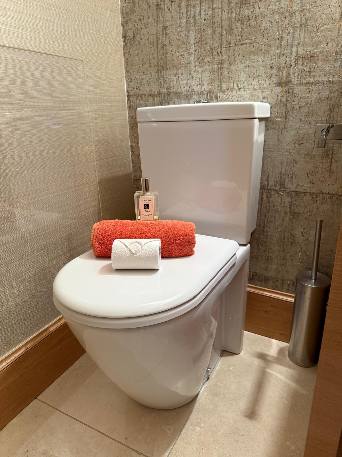 Cleaned guest WC finished with a rolled towel, a reed diffuser and fresh toilet roll