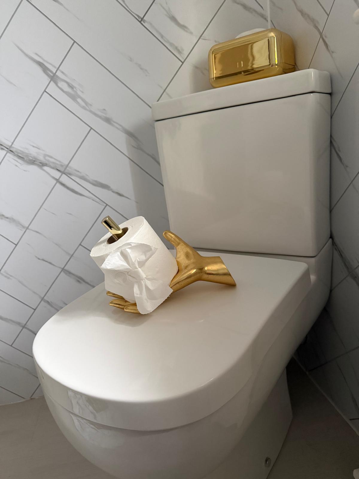 Marble-effect tiled cloakroom with polished gold fittings and a fresh toilet roll set out on the cistern