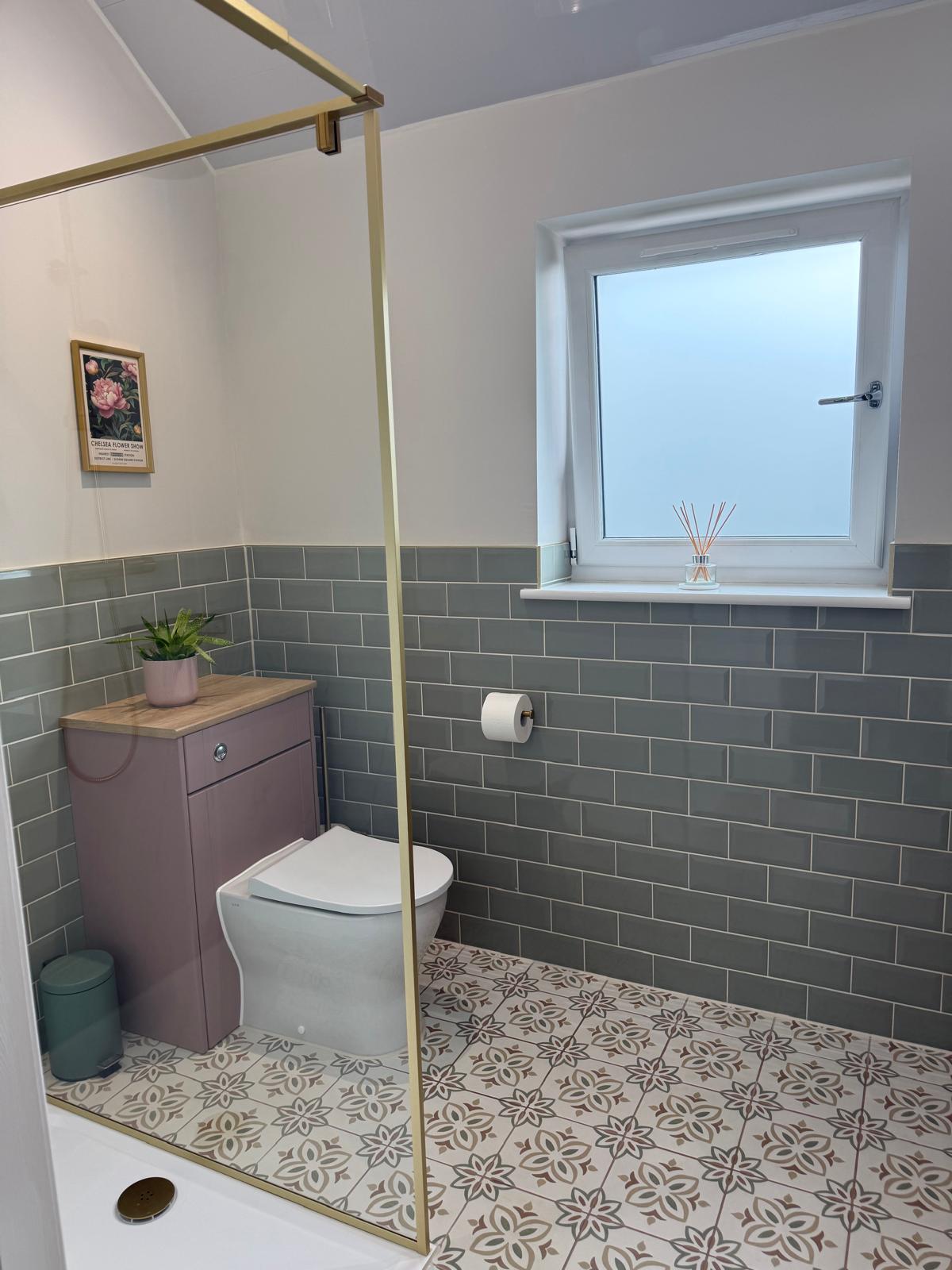 Family bathroom with sage green metro tiles, patterned floor tiles, a brass shower screen and a WC unit, cleaned throughout