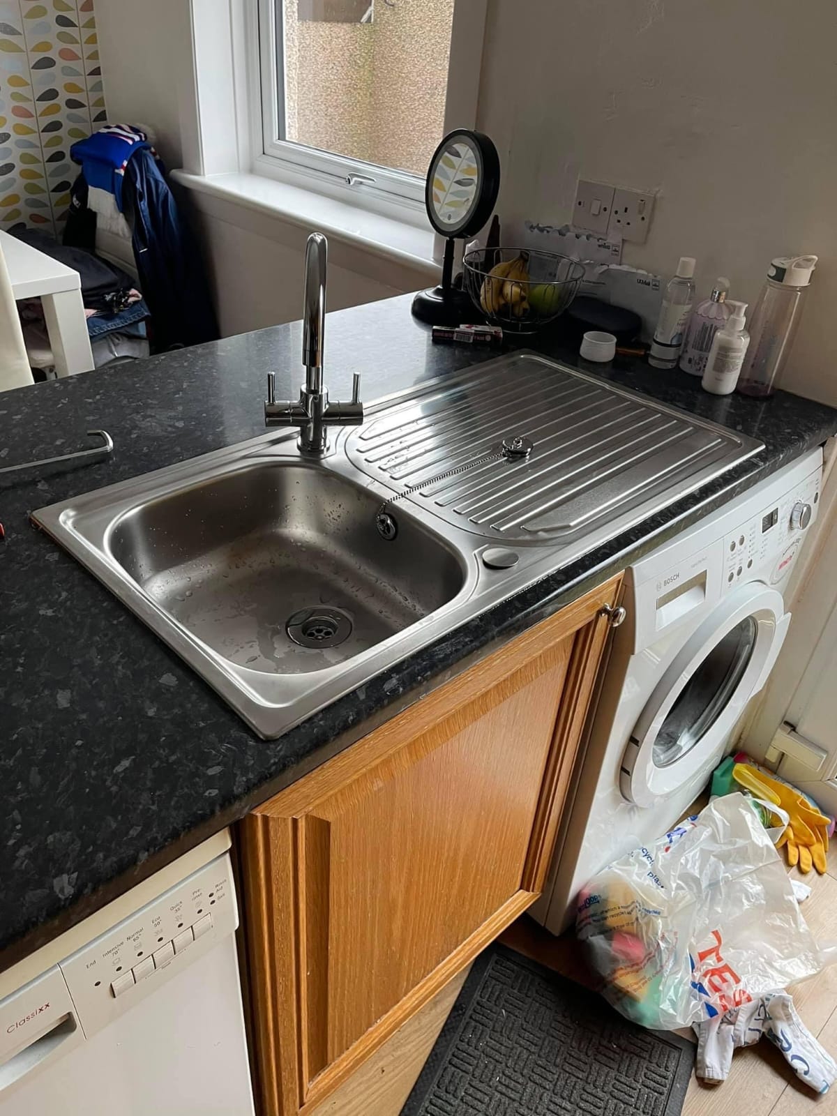 Chrome mixer tap on a stainless steel kitchen sink and drainer set into a black granite worktop
